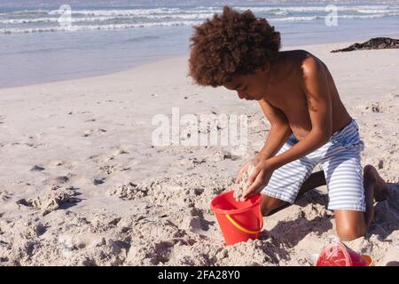 afroamericano ragazzo che si diverte a giocare con la sabbia al spiaggia Foto Stock