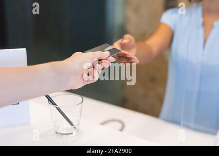 Donna d'affari diversa che indossa la chiave della camera da consegnare all'addetto alla reception hotel Foto Stock