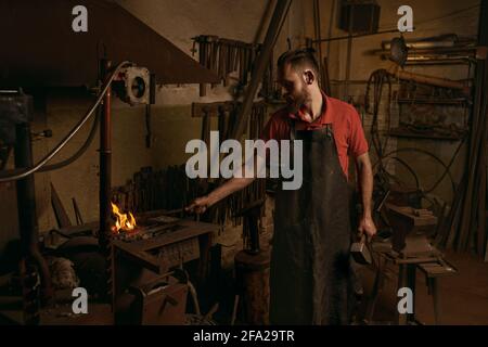 Fabbro che fa fiamme per lavorare in officina Foto Stock