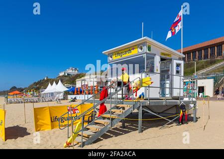 Bournemouth, Dorset UK. 22 aprile 2021. Tempo in Gran Bretagna: Bella calda e soleggiata in luoghi riparati, ma con una fresca brezza; abbondanza di sole e cielo blu alle spiagge di Bournemouth, in quanto pochi visitatori si dirigono verso il mare per godersi il sole. RNLI Lifeguard al chiosco bagnini tiene un'occhiata fuori. Credit: Carolyn Jenkins/Alamy Live News Foto Stock