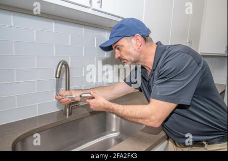 Idraulico che lavora su un rubinetto a spruzzo per un lavello da cucina in casa moderna Foto Stock