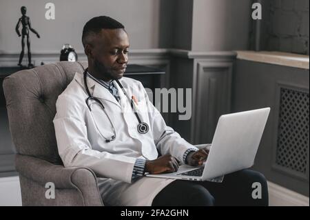 Medico dalla pelle scura che parla con Skype zoom con un computer portatile Foto Stock