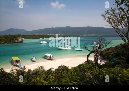 Barche ormeggiate in acque turchesi sul bordo di sabbia bianca a Kabira Bay, Isola di Ishigaki, Okinawa, Giappone Foto Stock