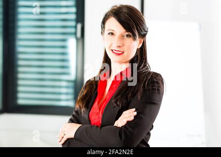 Business - Ritratto di una imprenditrice nel business vestiti in un ufficio, sorride alla telecamera Foto Stock