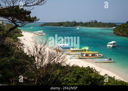 Barche ormeggiate in acque turchesi sul bordo di sabbia bianca a Kabira Bay, Isola di Ishigaki, Okinawa, Giappone Foto Stock