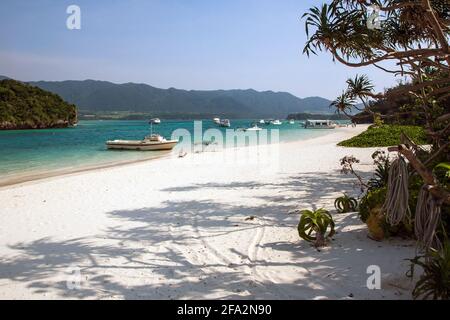 Barche ormeggiate in acque turchesi sul bordo di sabbia bianca a Kabira Bay, Isola di Ishigaki, Okinawa, Giappone Foto Stock