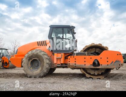 il grande rullo vibrante compatta il terreno. Lavori preparatori su strada. Affitto, acquisto leasing. Foto Stock