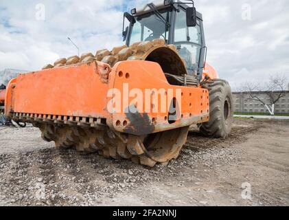 il grande rullo vibrante di seconda mano dimostra le sue qualità di compattazione della pietra frantumata. Lavori preparatori su strada Foto Stock