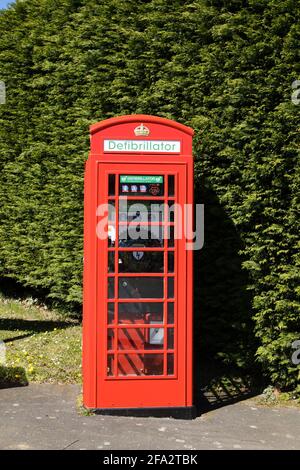 Tradizionale telefono britannico rosso, ora utilizzato per ospitare un defibrillatore nel villaggio di Denton. Lioncolnshire, Inghilterra Foto Stock