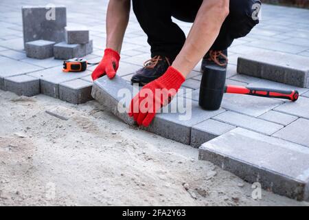 Il padrone in guanti gialli stende le pietre di pavimentazione Foto Stock