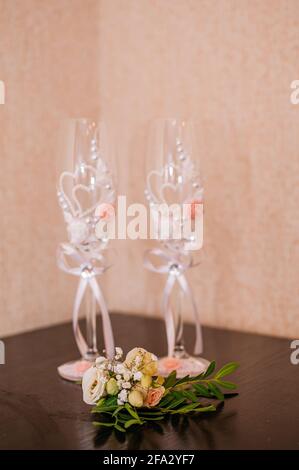 Bicchieri di champagne e boutonniere dello sposo su sfondo marrone Foto Stock