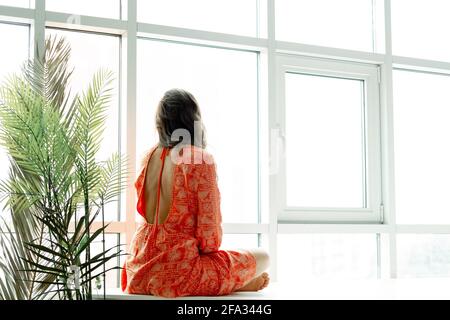 Lo Yoga a casa. Mantenere la calma. Attraente giovane donna seduta sulla posizione del loto sul pavimento con gli occhi chiusi. Foto Stock