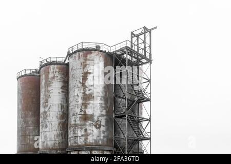 Vecchie cisterne abbandonate per immagazzinare prodotti industriali e fertilizzanti in uno stabilimento o in una fabbrica. Foto Stock