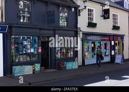 Vista di strada di una giovane donna che indossa una faccia che copre a piedi i negozi nella città mercato di Saffron Walden, Essex, Gran Bretagna, aprile 2021 Foto Stock