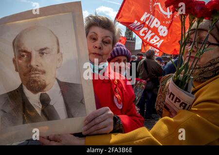 Mosca, Russia. 22 aprile 2021 UNA donna ha un ritratto del leader sovietico Vladimir Lenin mentre i sostenitori comunisti russi camminano per visitare il Mausoleo del fondatore sovietico Vladimir Lenin per celebrare il 151° anniversario della sua nascita, in Piazza Rossa nel centro di Mosca, Russia Foto Stock