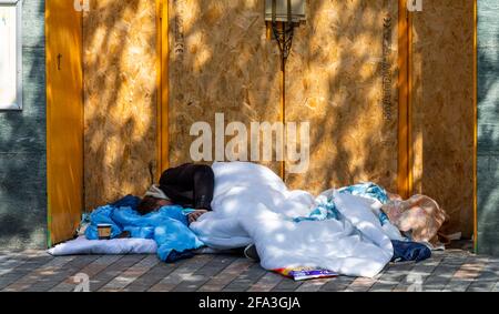 Senzatetto che dorme sconnesso nella porta del negozio. Foto Stock