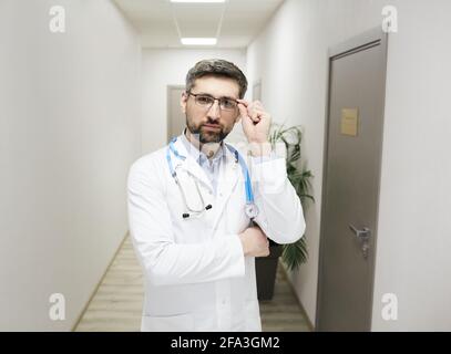 occupazione medica. Medico generico con esperienza che indossa occhiali e cappotto medico in piedi in una clinica medica, ritratto Foto Stock