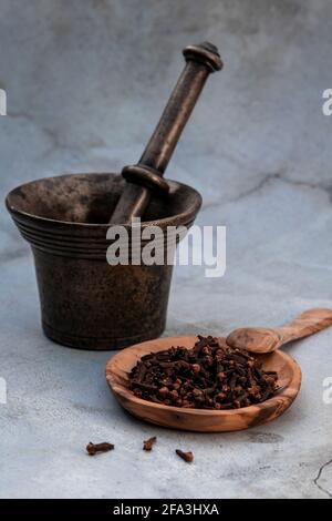 Mortaio metallico per la pooling e chiodi di garofano in un plate.cloves di legno sono le gemme aromatiche di fiore di un albero nella famiglia Myrtaceae, Syzygium aromaticum. Foto Stock