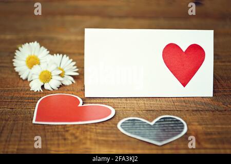 Tessera per il giorno delle madri con cuori e fiori su sfondo di legno Foto Stock