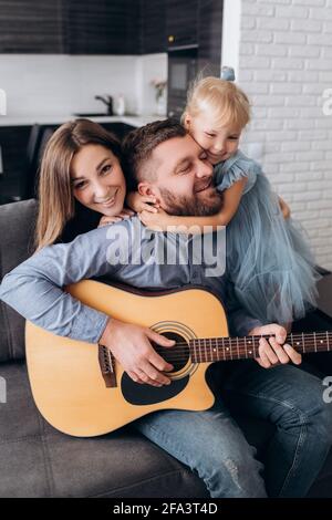 La famiglia suona la chitarra. Padre suona la chitarra per sua moglie e sua figlia. Foto Stock