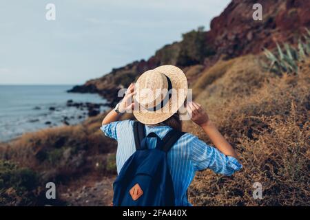 Donna viaggiatore a piedi sulla spiaggia di Akrotiri, Santorini isola, Grecia dal Mar Egeo godendo di paesaggio. Turismo, viaggi estivi Foto Stock