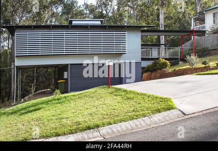 Casa Australiana molto moderna con tende di legno esterne sulla lato di una collina Foto Stock