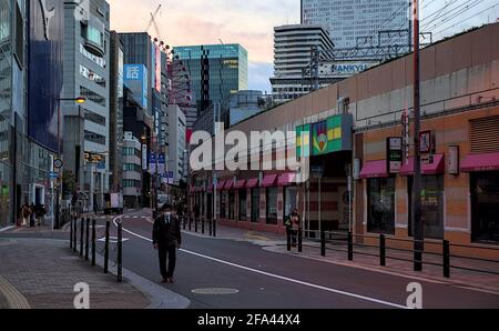 Osaka, Giappone - Ottobre 30 2020: Vista di prima mattina dei pedoni che camminano lungo una strada curva da una linea ferroviaria rialzata nel centro di Osaka Foto Stock