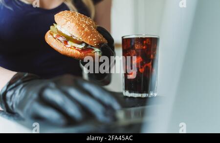 Donna che mangia hamburger rustici sul posto di lavoro. Foto Stock