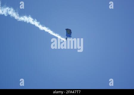 Il team Red Devils Parachute Display discende con un lungo fumo Percorre i campi di addestramento militare di Salisbury Plain sotto una nuvolosità cielo blu luminoso Foto Stock