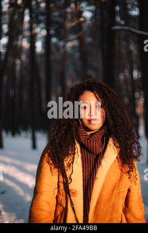 Ritratto di giovane donna in piedi nel parco durante l'inverno giorno di sole Foto Stock
