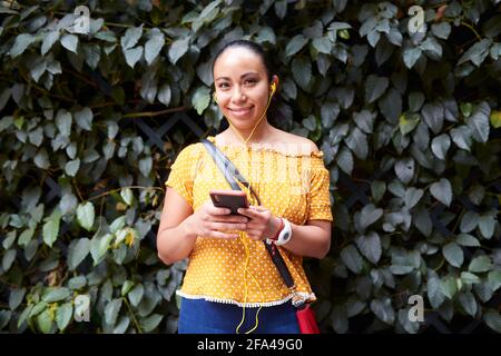 giovane donna che ascolta la musica attraverso il suo smartphone sul via Foto Stock
