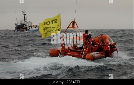 GLI ATTIVISTI DI GREENPEACE NEL CANALE INGLESE CERCANO DI SOLLEVARE UN BOA DA UNA BARCA FRANCESE NEL TENTATIVO DI PREVENIRE LORO DALLA PESCA DURANTE LA LORO CAMPAGNA CONTRO TWIN TRAWLER PESCA PER IL BASSO DI MARE CHE STA UCCIDENDO GRANDI NUMERI DI COMONE DELFINI.23 MARZO 2005 TOM PILSTON Foto Stock