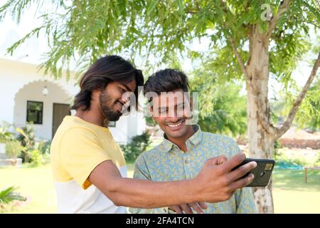 Sorridente amici indiani che prendono un selfie in un parco Foto Stock