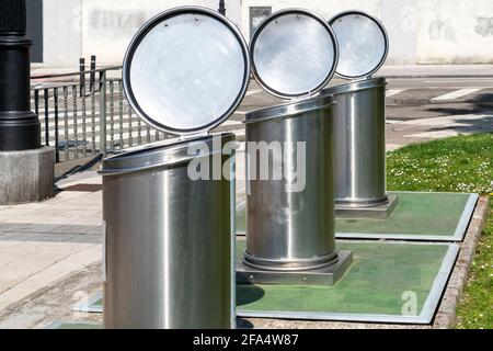 Contenitori di rifiuti in metallo vuoti con coperchi aperti su una strada cittadina per smistare i rifiuti. Tre contenitori. Concetto ecologico Foto Stock