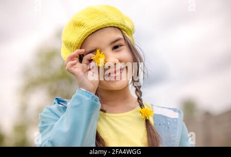 Ritratto di una simpatica bambina con due spirali, in un berretto giallo lavorato a maglia Foto Stock