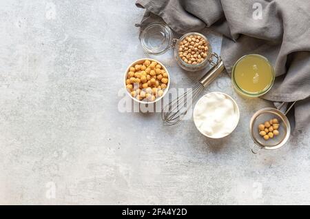 Acqua di ceci in scatola aquafaba. Sostituzione delle uova e sostituti. Prodotti vegani, sostenibili e naturali eco-friendly. Tavolo in marmo, copy s Foto Stock