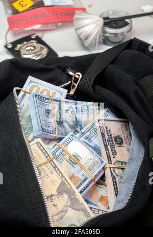 Sacchetto nero pieno di banconote in dollari in unità investigativa criminale, immagine concettuale Foto Stock