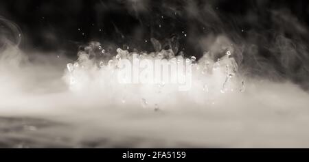 BANNER astratto. Vera nube di fumo Mystic con gocce d'acqua che esplodano, movimento del mosca del vapore, sfondo scuro. Esperimento chimico, aromaterapia, bevanda bruciata Foto Stock