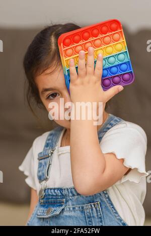 Bambino giocando Poppit Fidget Toy. Giovane piccola ragazza a casa