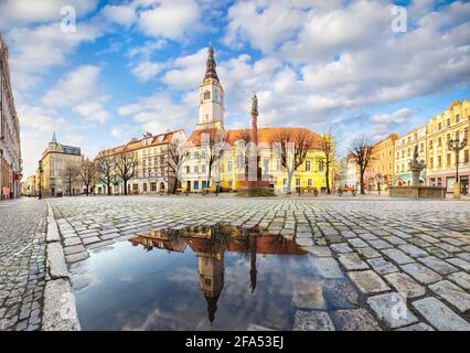Swidnica, Polonia. Panorama della Piazza del mercato (Rynek) con l'edificio del Municipio storico che si riflette in puddle Foto Stock