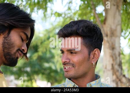 Messa a fuoco superficiale di due giovani amici maschili indiani bei dentro un parco Foto Stock
