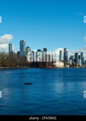 I massicci e imponenti grattacieli del quartiere finanziario di Canary Wharf, visti dall'altra parte delle acque del molo della Groenlandia. Foto Stock