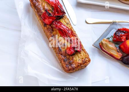 Dolce salato sano fatto in casa con verdure e peperoni rossi arrostiti sulla parte superiore. Forme rettangolari su sfondo di marmo bianco. Piattini di vetro, posate d'oro e un asciugamano. Foto di alta qualità, vista dall'alto Foto Stock