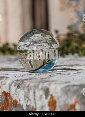 Crystal Photo Ball sulla superficie in granito grigio che riflette l'immagine di Chiesa e edificio storico sotto il sole estivo Foto Stock