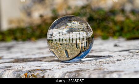 Crystal Photo Ball sulla superficie in granito grigio che riflette l'immagine di Chiesa e edificio storico sotto il sole estivo Foto Stock