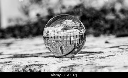 Crystal Photo Ball sulla superficie in granito grigio che riflette l'immagine di Chiesa e edificio storico sotto il sole estivo Foto Stock