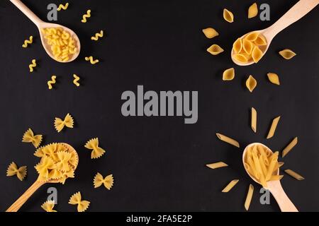 Diversi tipi di pasta in cucchiai di legno sul tavolo. Vista dall'alto. Foto Stock