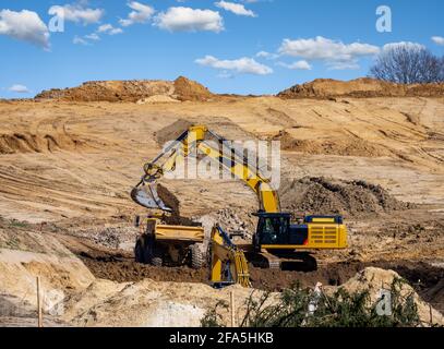 Falda terra gialla che riempie un autocarro in un cantiere Foto Stock