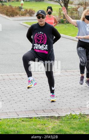 Una donna in una lezione di danza Zumba in un parco a Queens, New York City. Foto Stock