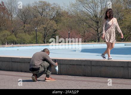 In un tranquillo giorno feriale di primavera, una coppia scatta foto al telefono cellulare vicino all'Unisphere su Flushing Meadows Corona Park a Queens New York City. Foto Stock
